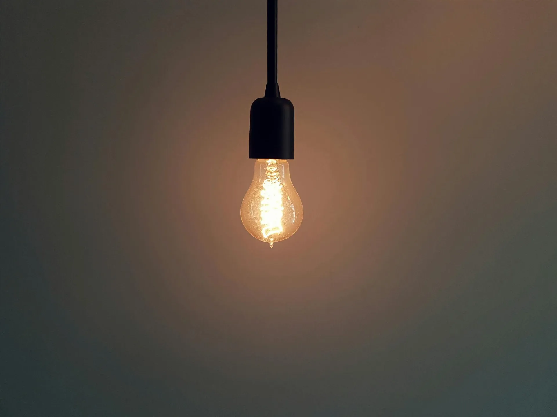 A warm filament bulb glowing on a black pendant fitting