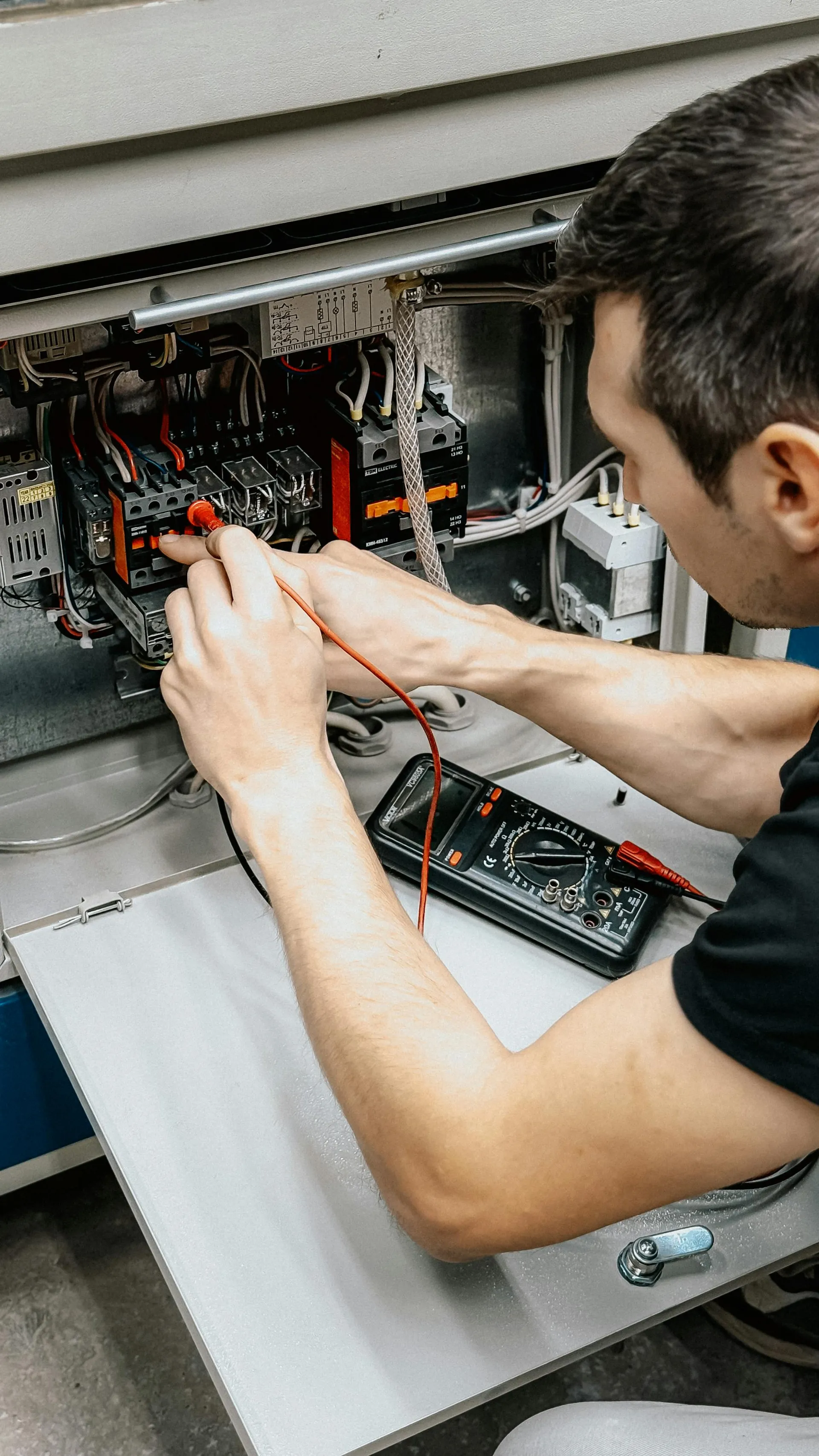 Electrician taking a reading on an electrical panel with a multimeter