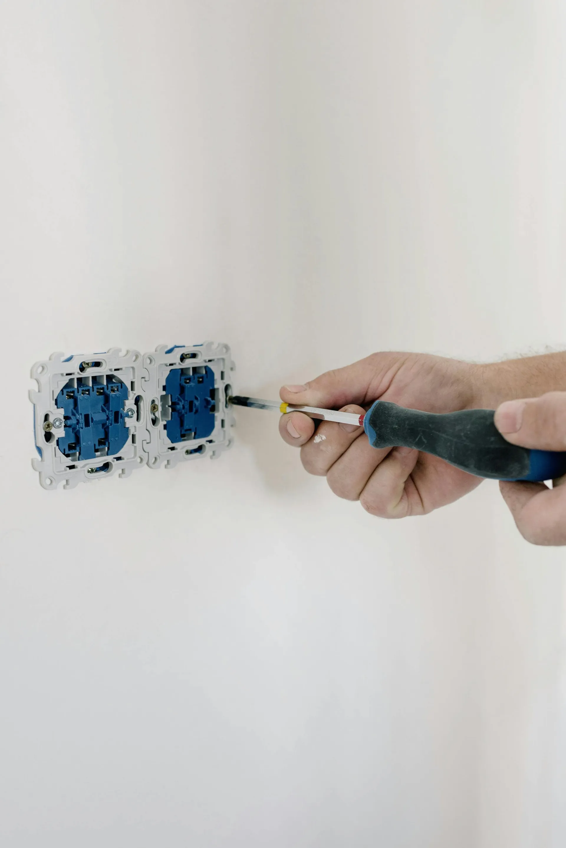 Hands fitting a double socket back-box to a plastered wall
